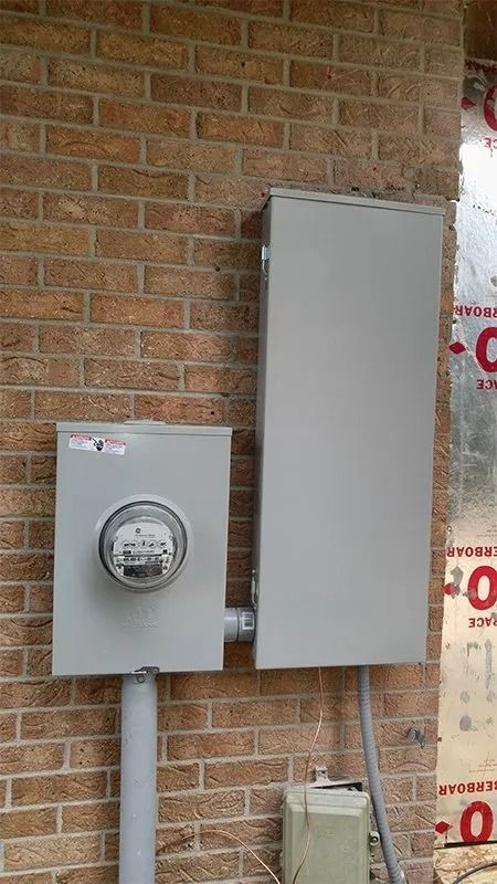 A brick wall with a meter and a box on it.