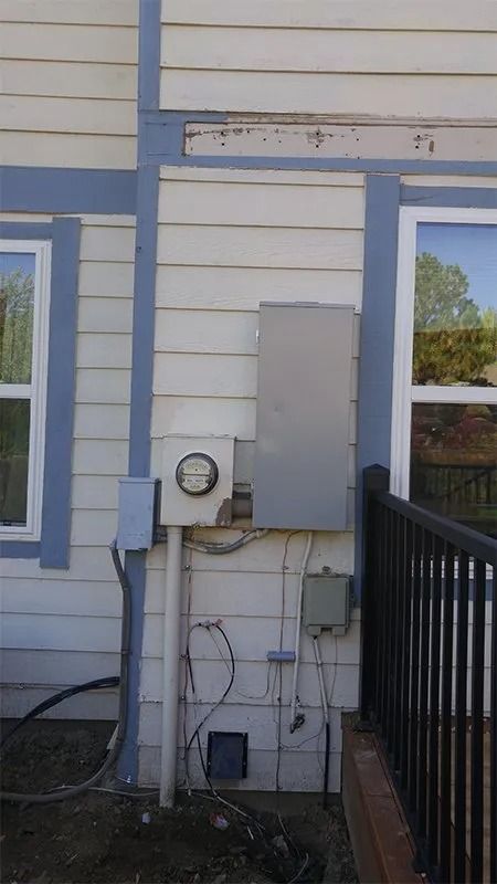 A white house with blue trim has a meter on the side of it.