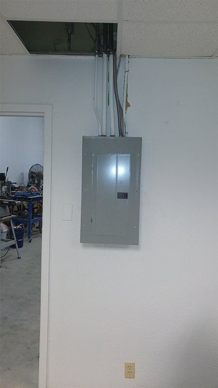 An electrical box is hanging from the ceiling in a room.