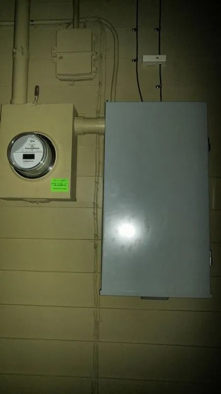A meter is hanging on a wall next to a box.