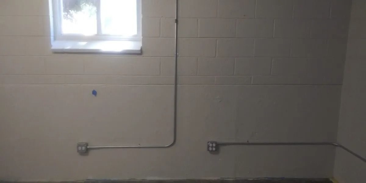 A room with a window and a pipe on the wall.