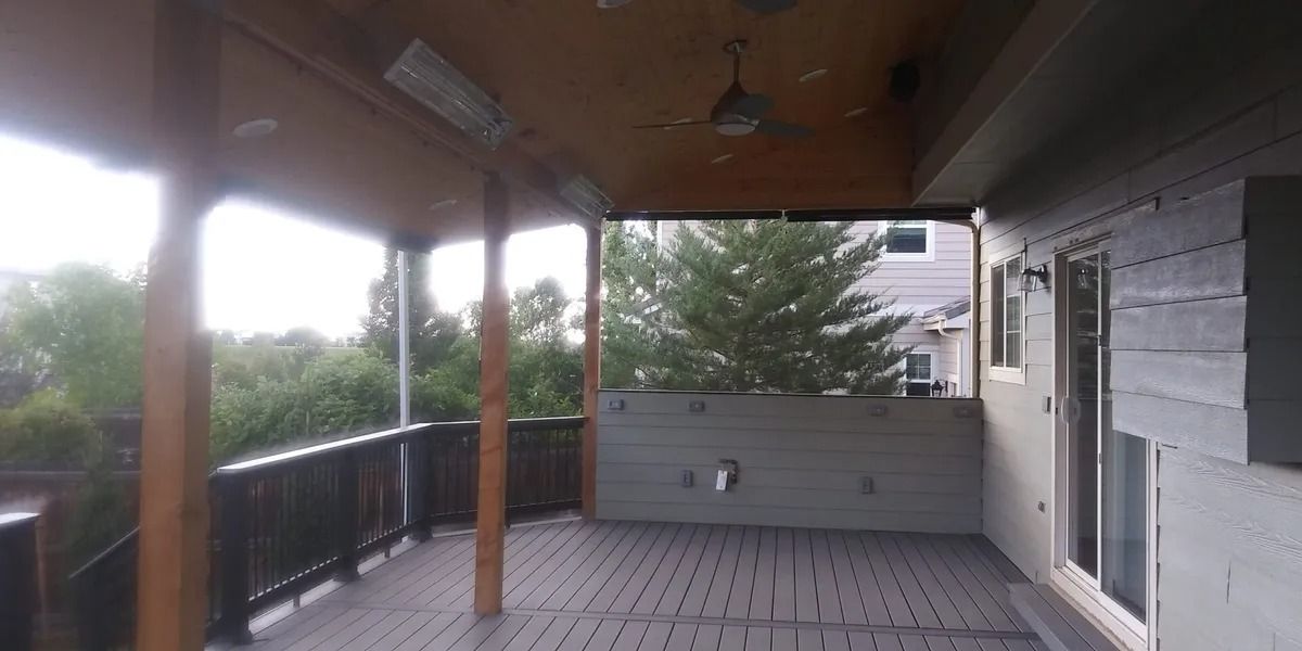 An empty porch with a ceiling fan and trees in the background