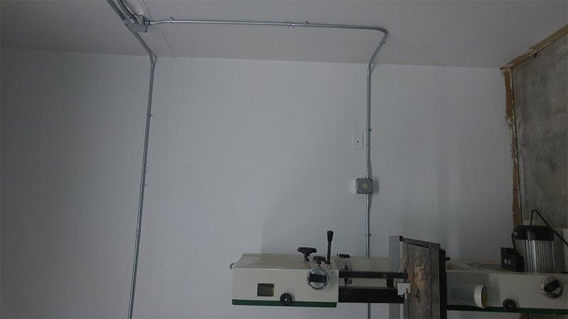 A white wall with a few electrical wires hanging from it