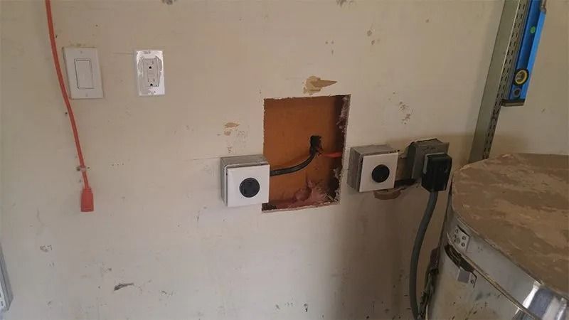 There is a hole in the wall with electrical wires coming out of it.