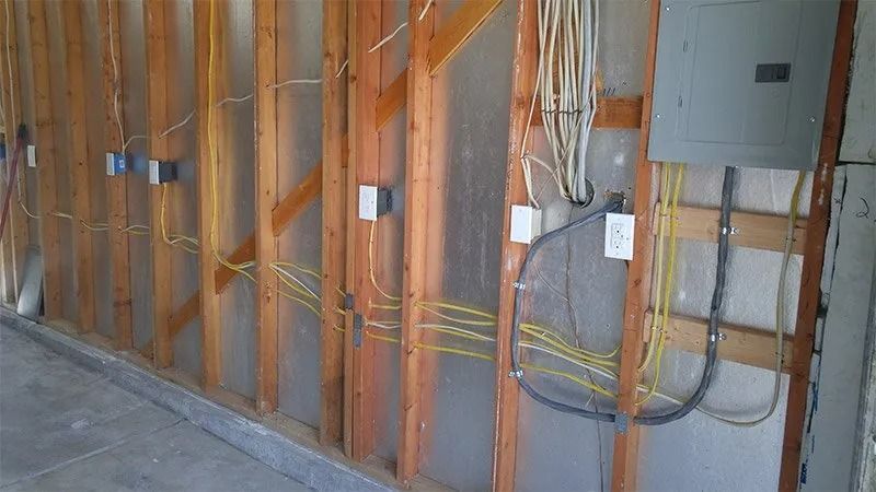 A wall with wooden beams and electrical wires coming out of it.