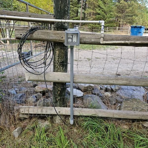 A wooden fence with a power outlet attached to it.