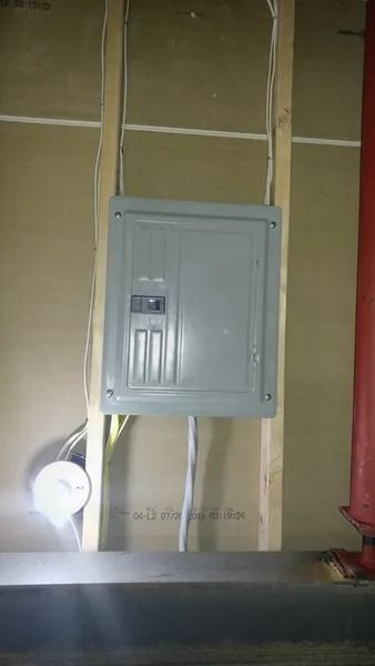 A electrical box is hanging on a wall in a room.