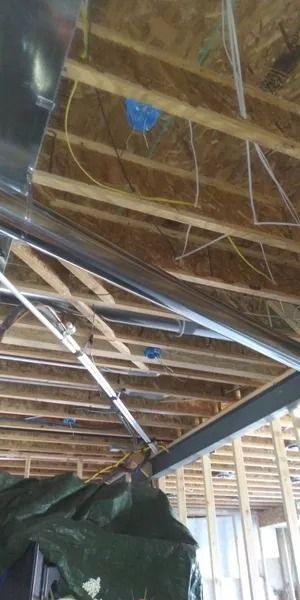 A ceiling with a lot of wooden beams and wires hanging from it.