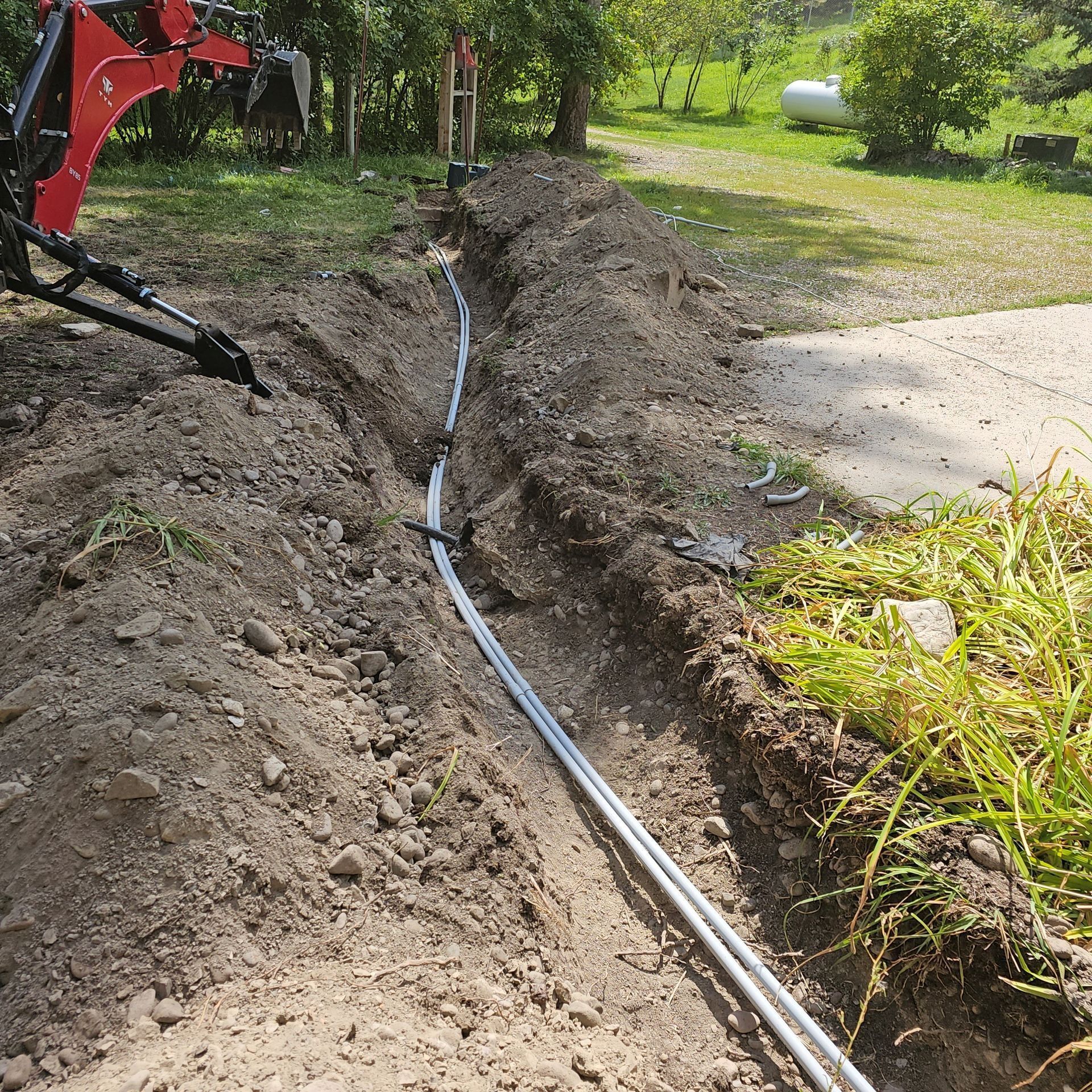 A hose is being installed in the dirt next to a road.