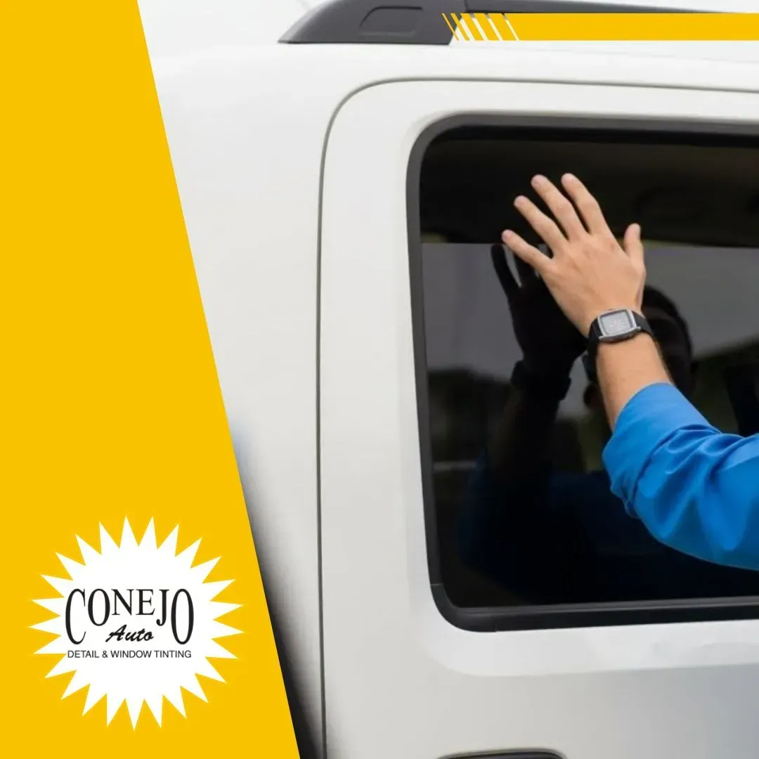 Hand in blue sleeve waving from a white vehicle window with a yellow Conejo logo.