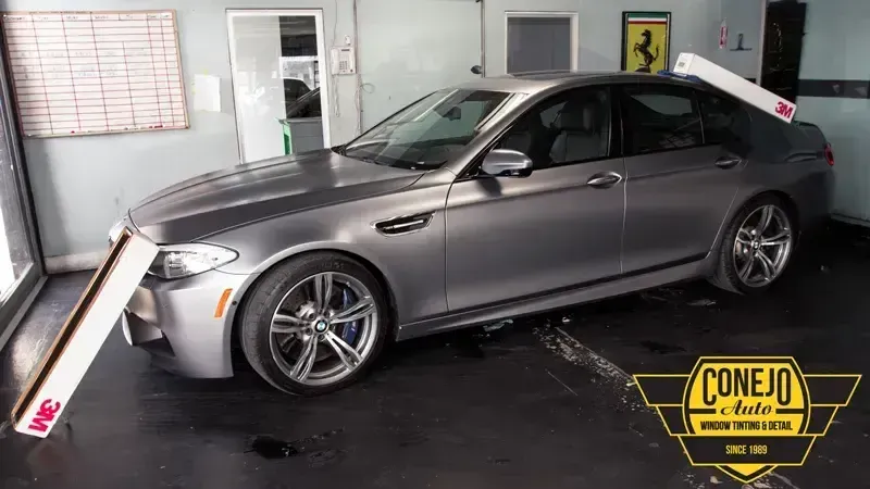 Silver sedan in an indoor auto shop, parked near a Cone 10 archery target setup.