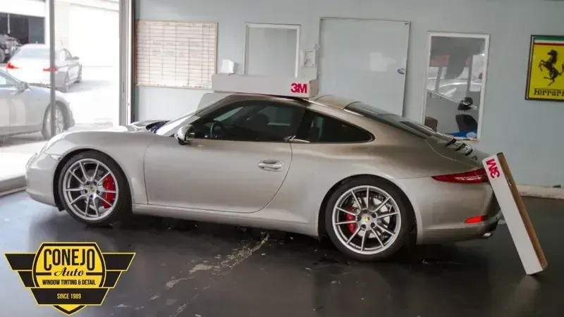 Silver Porsche 911 parked indoors at a car showroom, side view with race wheels and red brake calipers