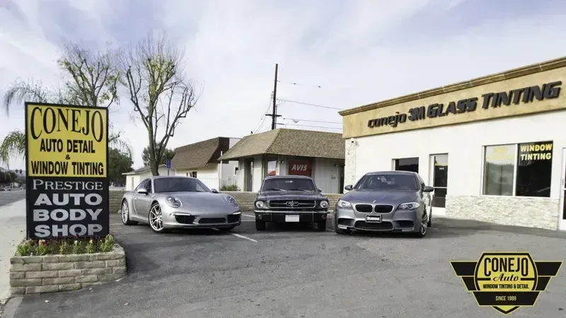 Car lot with three cars in front of Conejo Auto Detail, window tinting, and auto body shop buildings