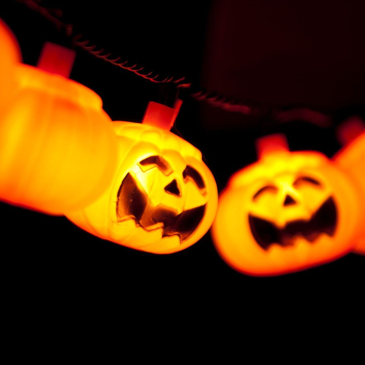 A string of halloween pumpkins glowing in the dark.