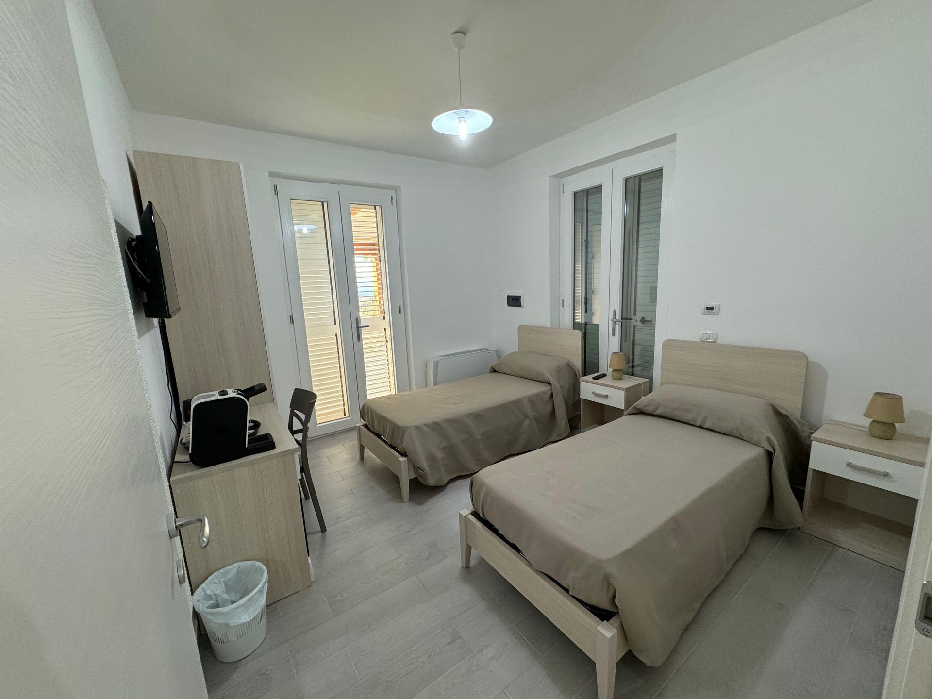 Una camera con due letti e un bidone della spazzatura