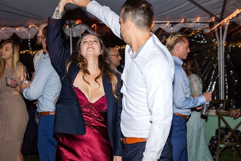 A group of people are dancing under a tent at a wedding reception.