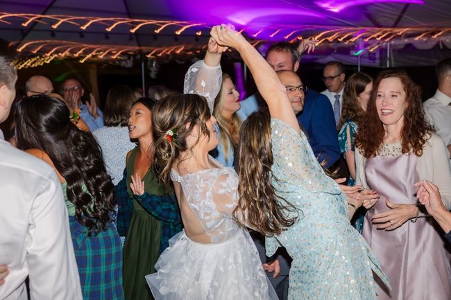 A group of people are dancing at a wedding reception.