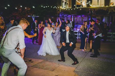 A group of people are dancing at a wedding reception.