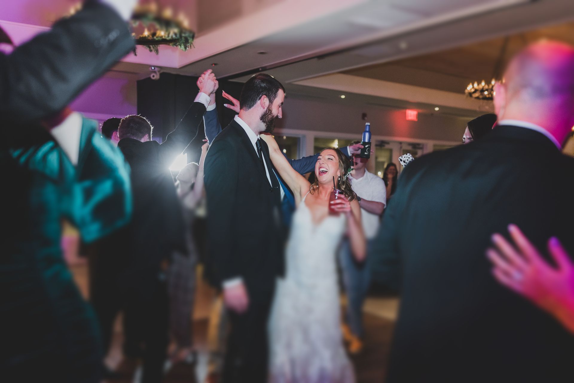 Bride and groom dance at a wedding reception with guests in the background.