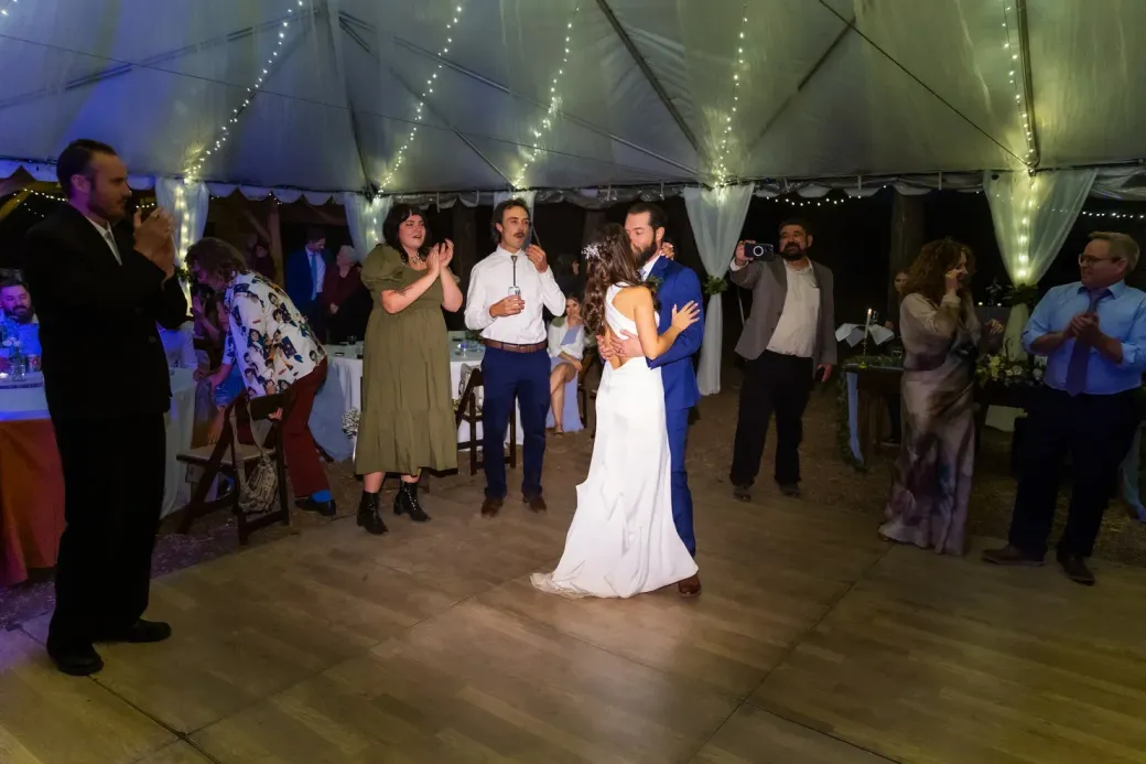 A bride and groom are dancing under a tent at their wedding reception.