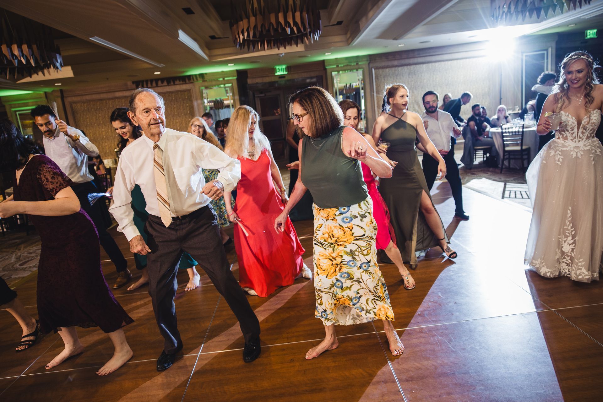 A group of people are dancing on a dance floor at a wedding reception.