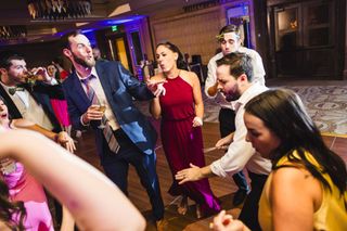 A group of people are dancing on a dance floor at a wedding reception.