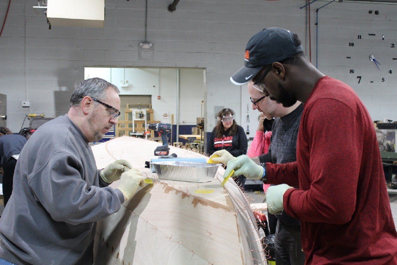 Keith and Charles are applying materials to the Row4Kids boat