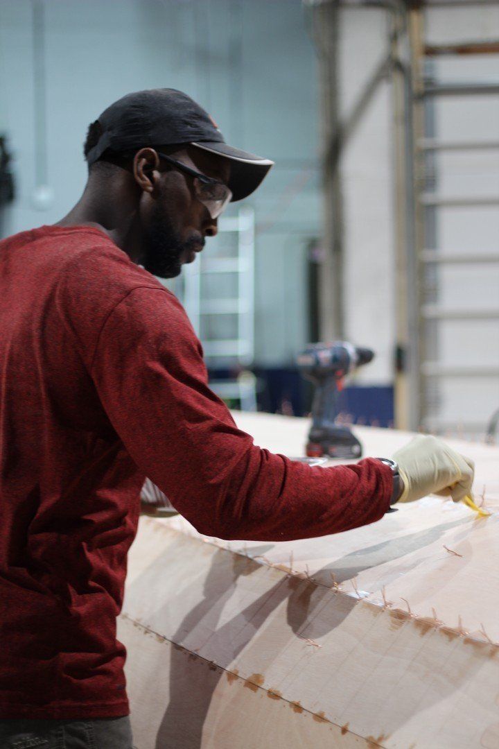 Charles is applying materials to the Row4Kids boat