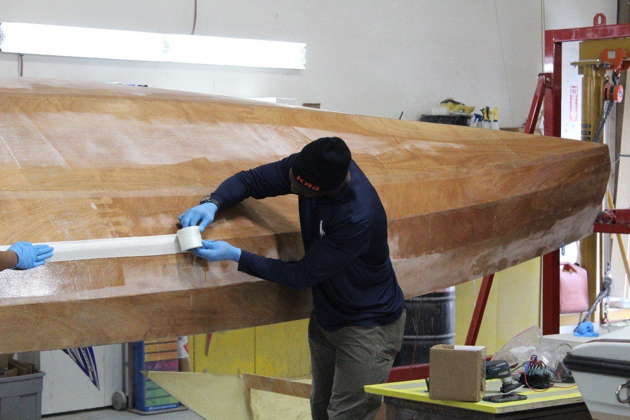 Charles applies materials to the Row4Kids boat