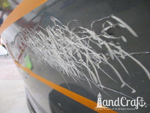 Close up picture of scratches through paint on an aluminum Lund boat