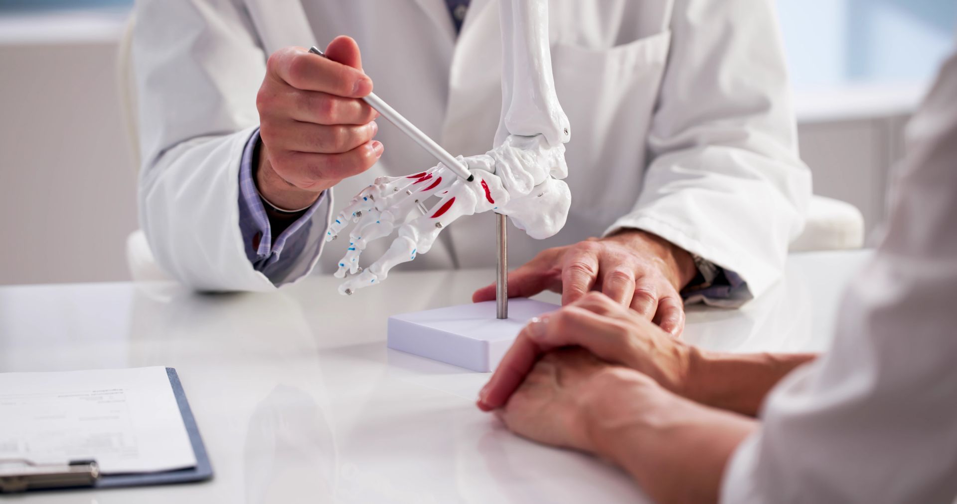 Podiatrist explaining foot structure using a model while consulting with a patient.