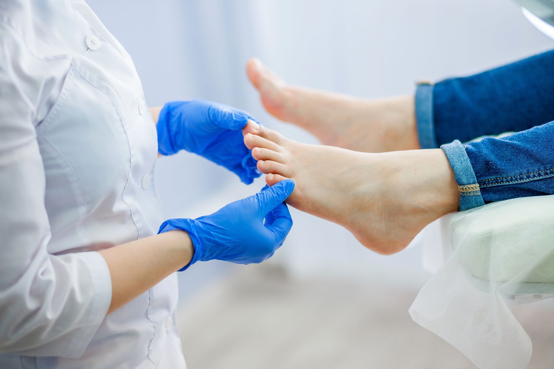A podiatry doctor, wearing blue gloves, examines a patient's foot. A podiatry doctor, wearing blue gloves, examines a patient's foot.