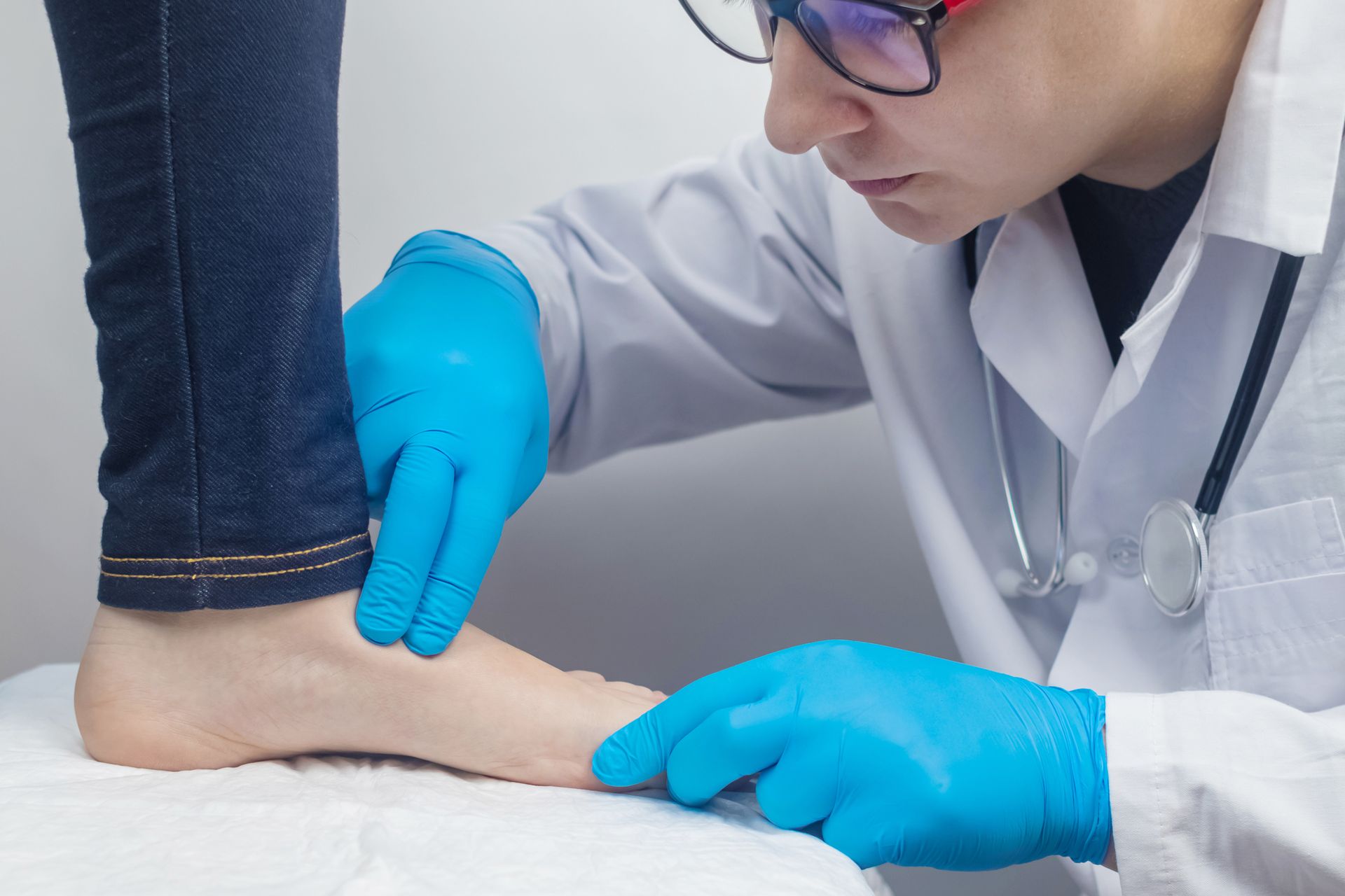 Doctor examines foot while wearing gloves and stethoscope. Doctor examines foot while wearing gloves and stethoscope.