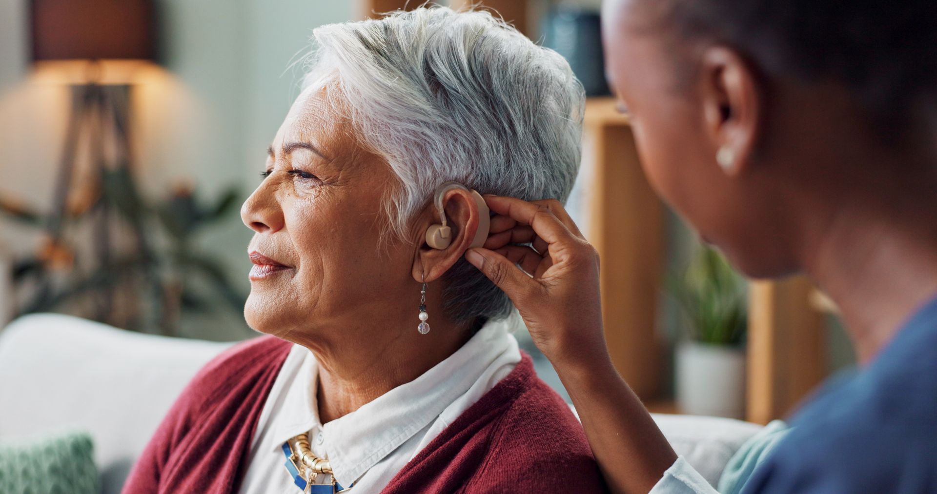 A nurse assists a woman with a hearing aid and provides medical support and wellness technology.
