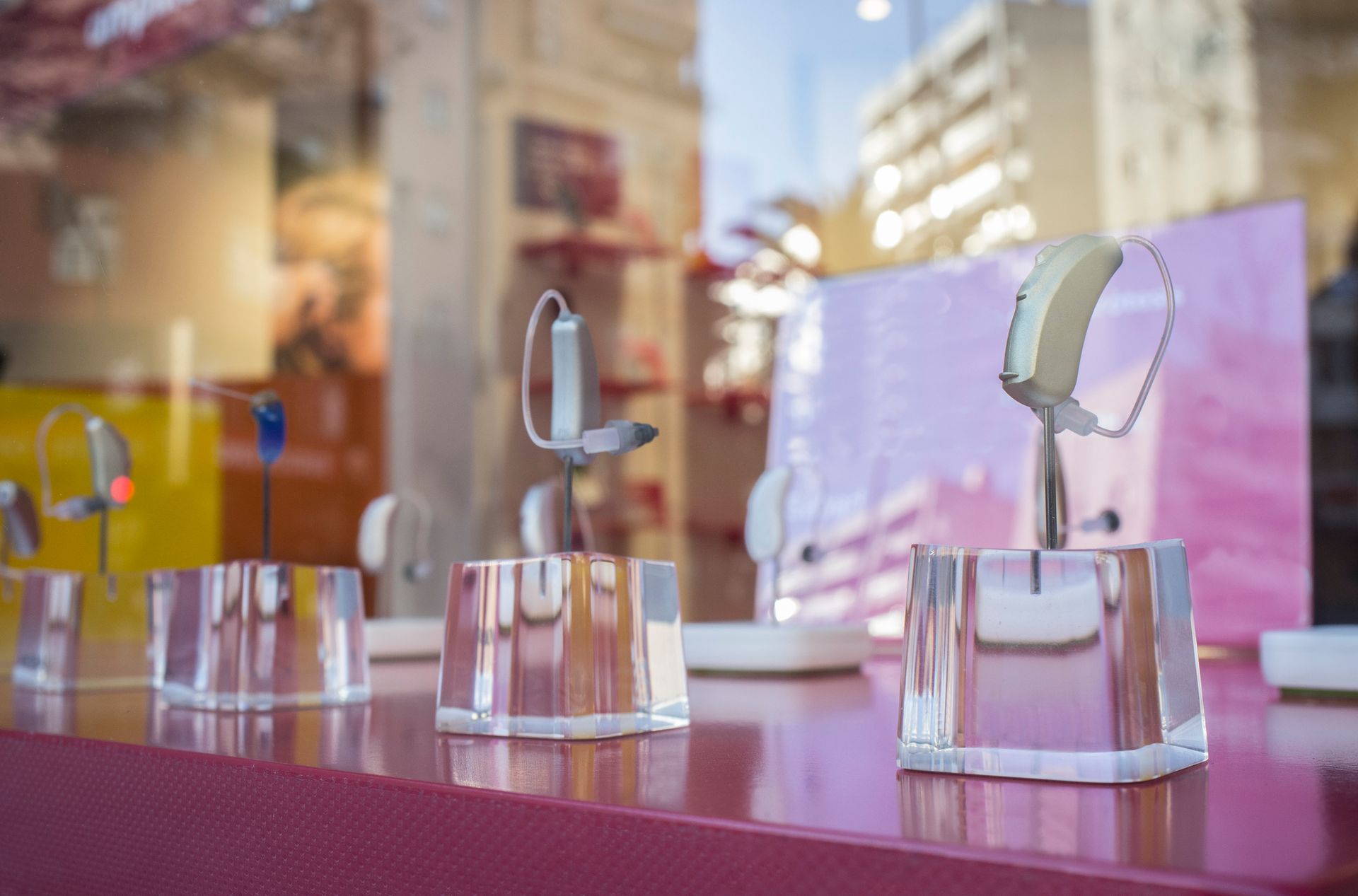 Hearing aid store window featuring stylish hearing devices arranged neatly under bright lighting.