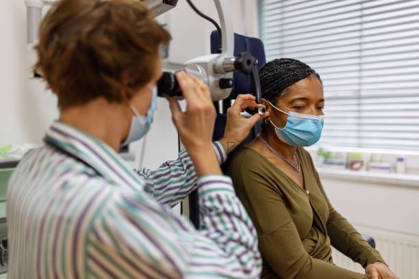 Audiology specialist examining patient’s ear with otoscope during hearing assessment.