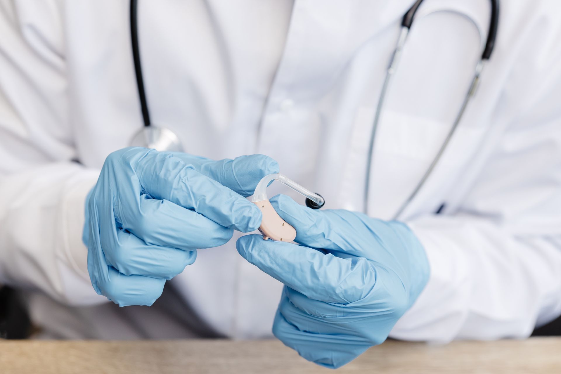 An otolaryngologist holds a hearing aid in his hands.
