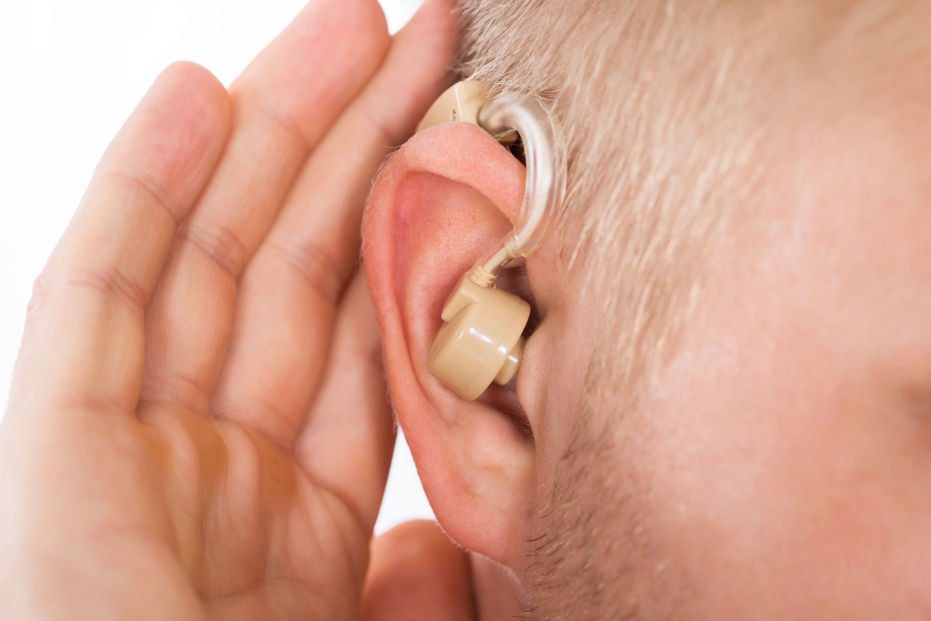Person adjusting behind the ear hearing aid for better hearing support.