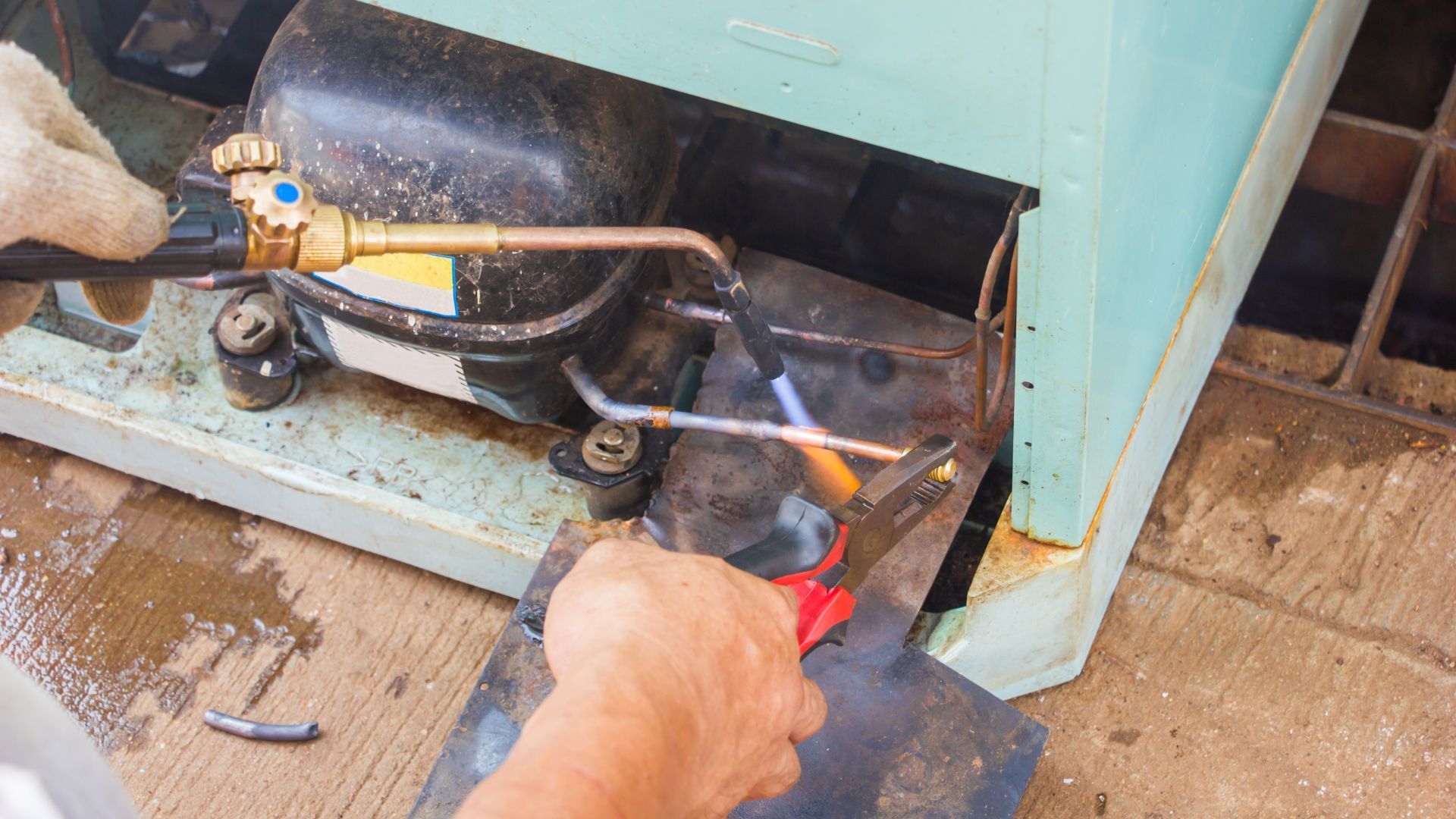 A person is welding a refrigerator with a torch.