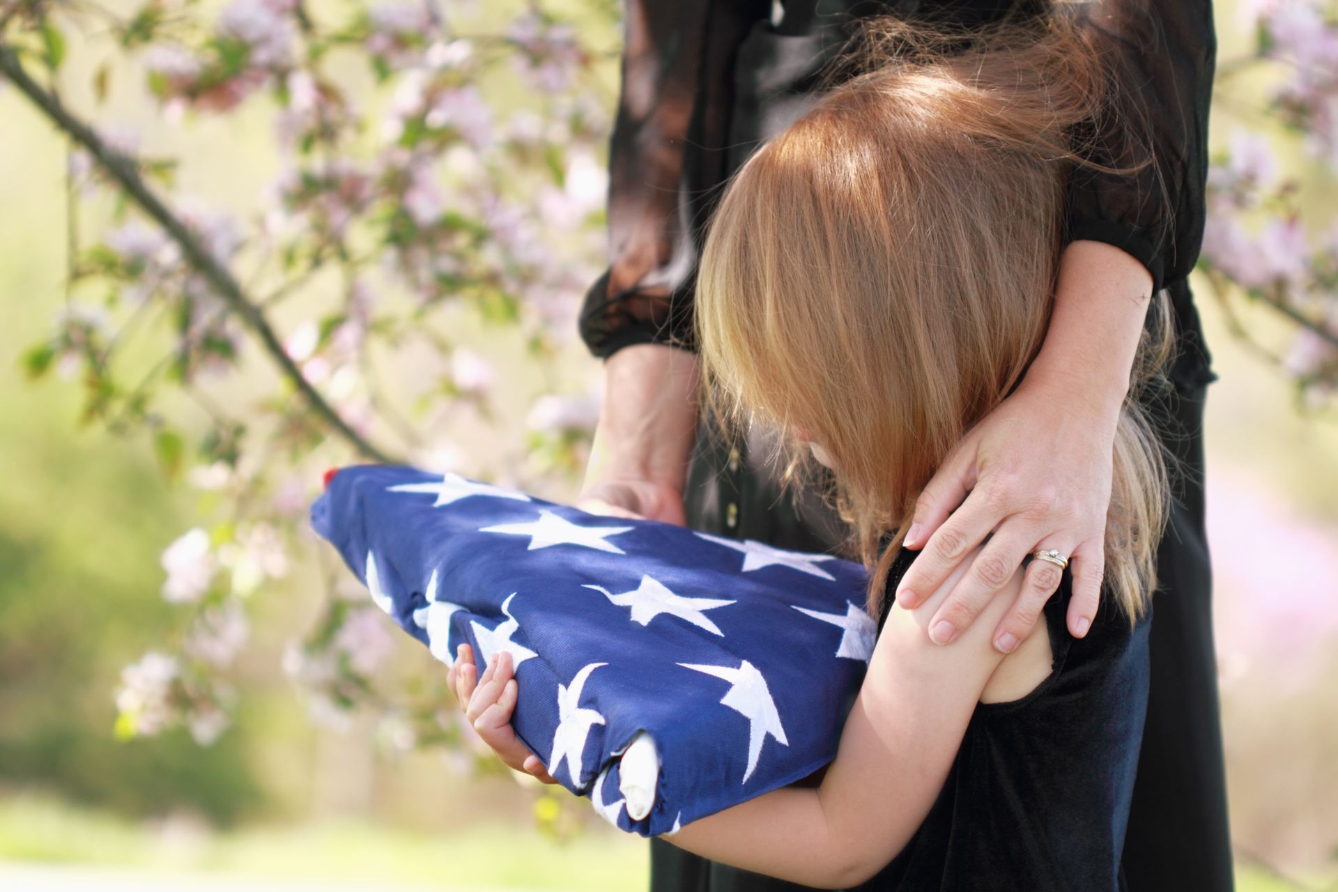 a little girl holding the flag of a diseased military service member