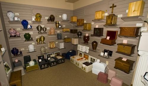 A display of urns in various shapes, colors, and materials on shelves in a showroom.