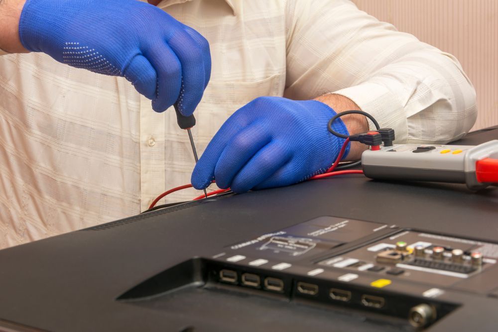 A Man Wearing Blue Gloves is Working on a Television — Garrow's TV & Antenna Services in Caloundra West, QLD