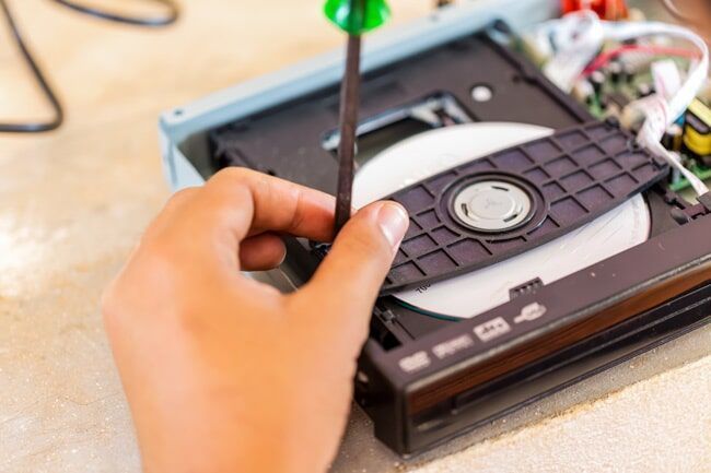 A Person is Fixing a DVD Player With a Screwdriver — Garrow's TV & Antenna Services in Maroochydore, QLD