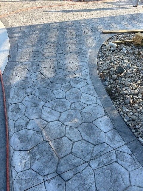 Stamped concrete pathway with a gray stone pattern, bordered by a curved edge.