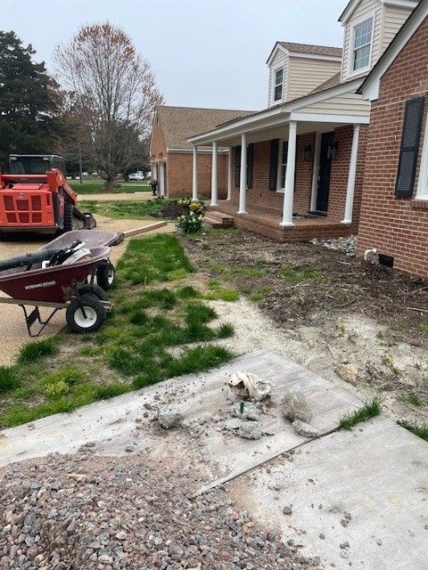 Construction site: home's front yard torn up, with a path, brick home, and construction equipment in the background.