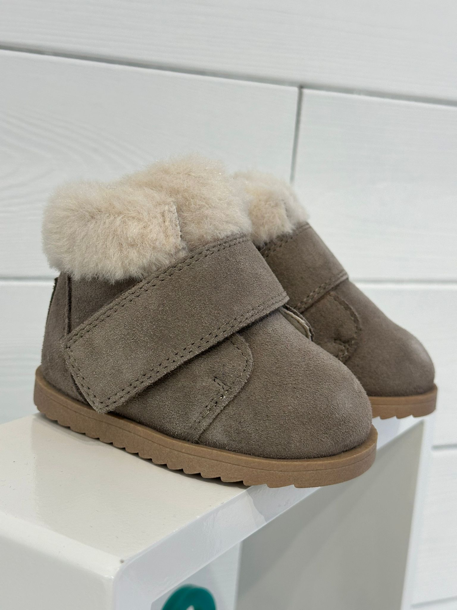 Stivaletti per bambini in pelle scamosciata marrone con finiture in montone color cuoio e chiusura con cinturino in velcro.