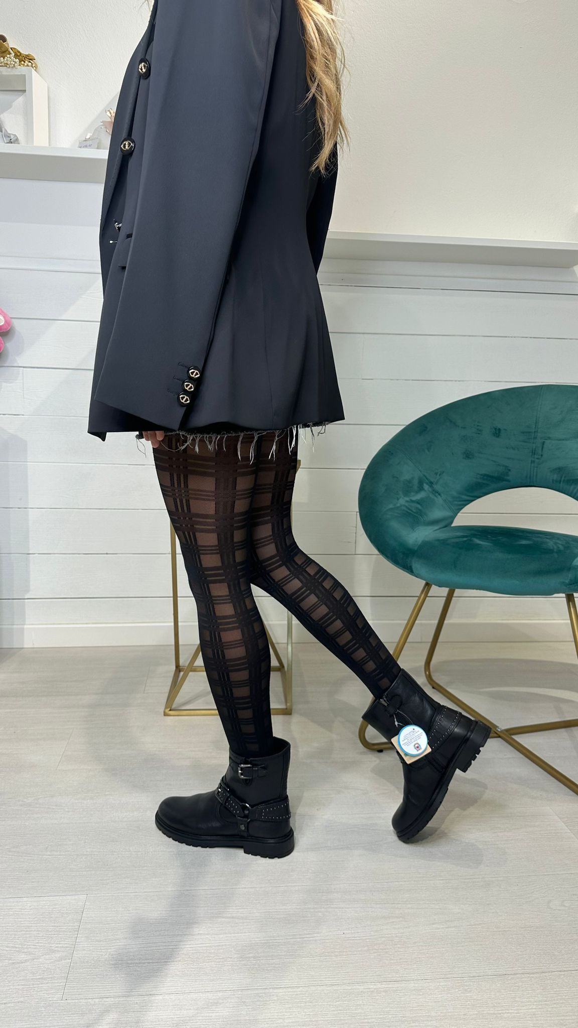 Persona che indossa un blazer nero, calzamaglia fantasia e anfibi.