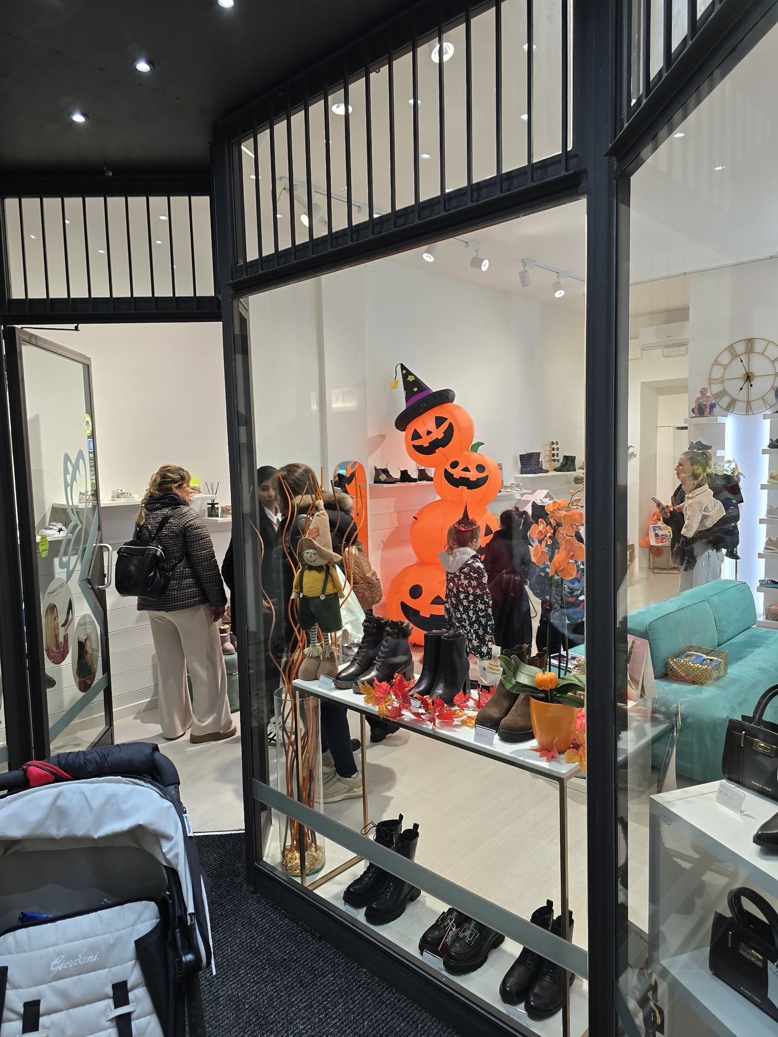 Vetrina di un negozio di scarpe con zucche di Halloween. Persone che guardano le scarpe all'interno di un negozio.