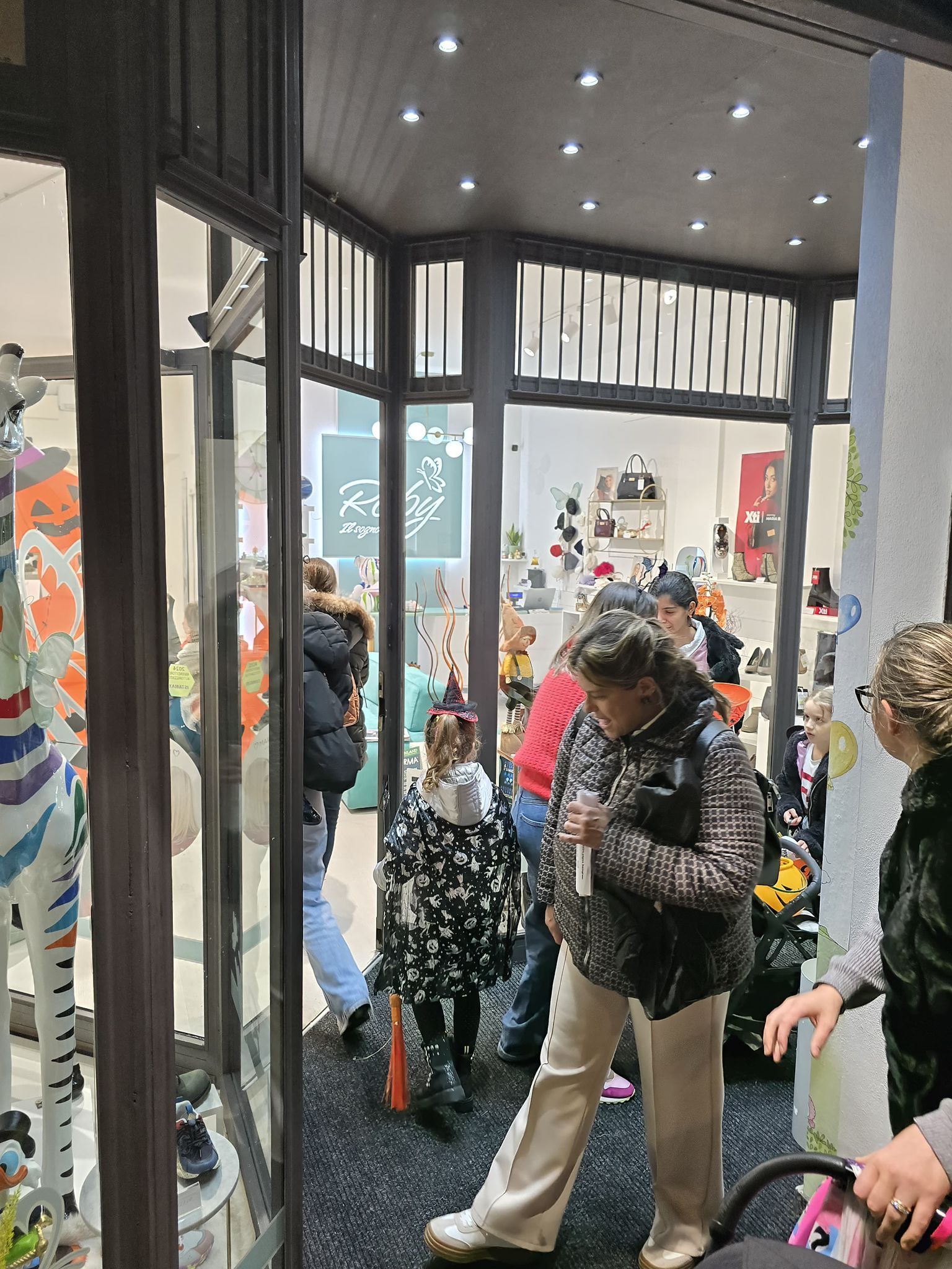 Persone che guardano in una vetrina. All'interno, la merce è visibile. Cornice nera e marrone.