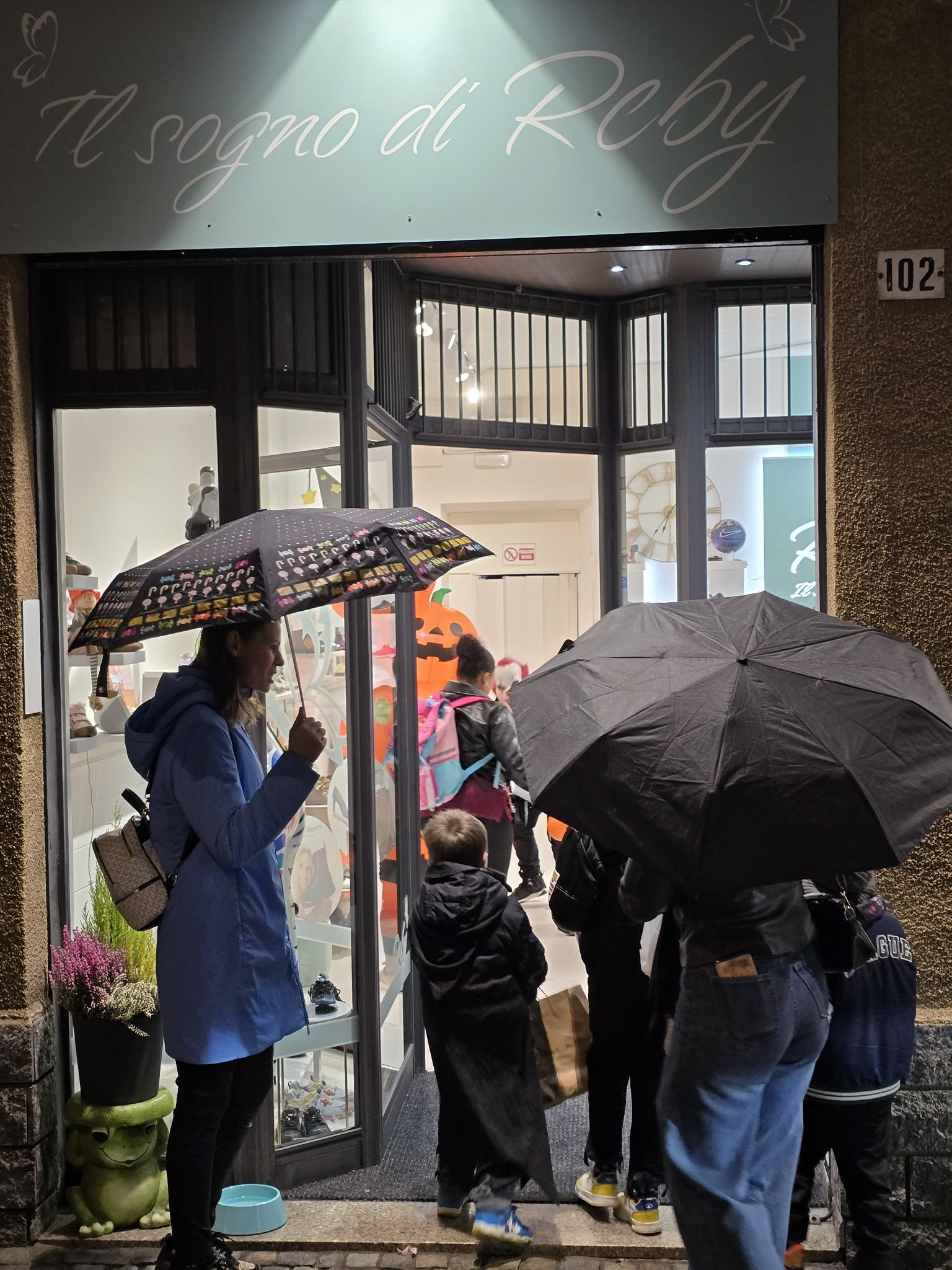 People with umbrellas entering a shop